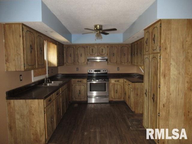 kitchen featuring sink, ceiling fan, a tray ceiling, dark hardwood / wood-style flooring, and stainless steel range with electric cooktop