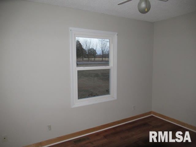 unfurnished room featuring ceiling fan, dark hardwood / wood-style flooring, and a textured ceiling