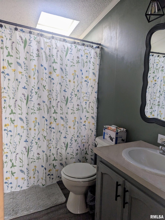 bathroom with a skylight, vanity, ornamental molding, a textured ceiling, and toilet