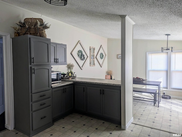 kitchen featuring pendant lighting, gray cabinets, a textured ceiling, and ornate columns