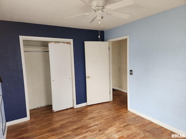 unfurnished bedroom featuring hardwood / wood-style floors, a closet, and ceiling fan