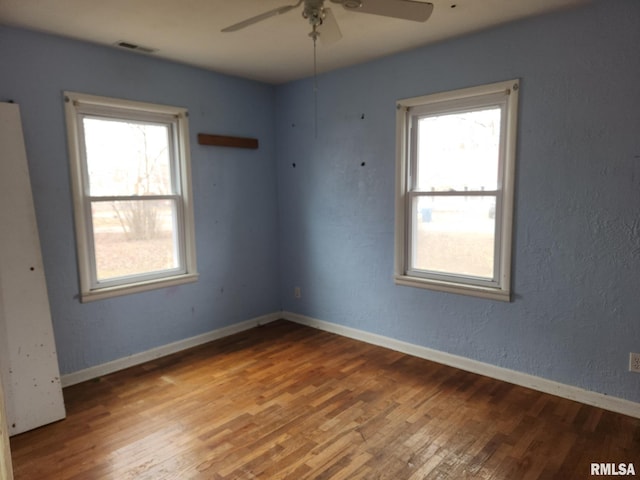 empty room with hardwood / wood-style flooring, ceiling fan, and plenty of natural light