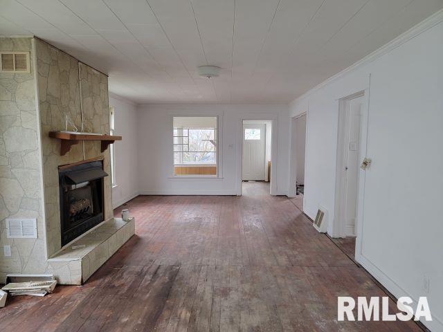 unfurnished living room featuring hardwood / wood-style flooring, a large fireplace, and ornamental molding