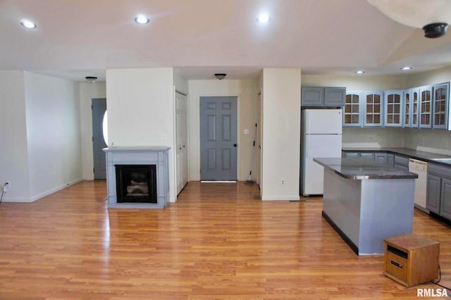 kitchen featuring white appliances, gray cabinets, a center island, and light wood-type flooring