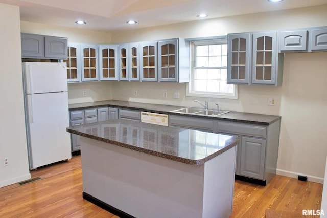 kitchen featuring gray cabinetry, sink, white appliances, and a kitchen island