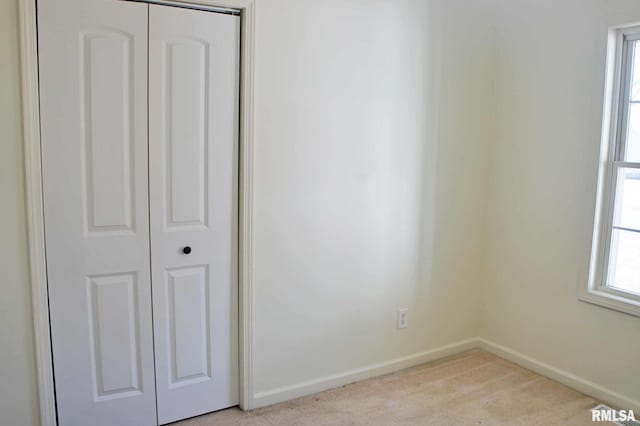 unfurnished bedroom featuring light carpet and a closet