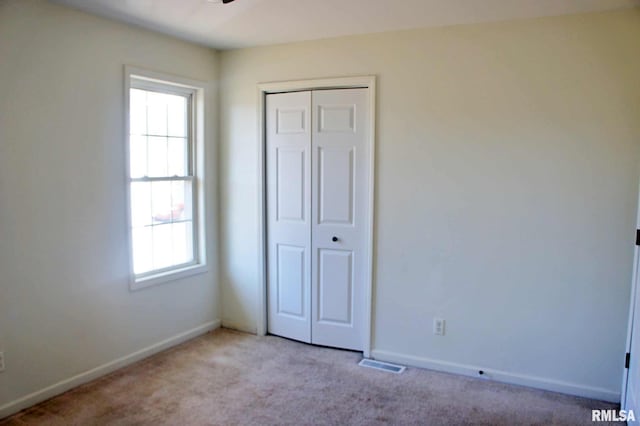 unfurnished bedroom featuring light colored carpet and a closet