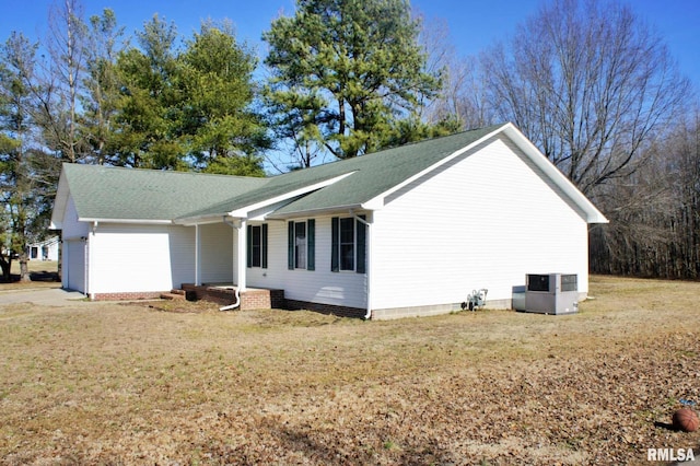 view of side of home with a garage, a yard, and central AC unit