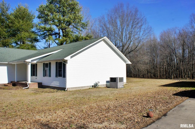 view of side of home with central AC unit and a yard