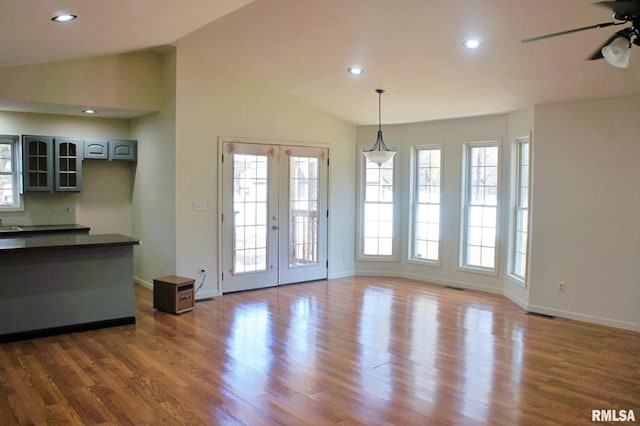 unfurnished dining area with lofted ceiling, dark wood-type flooring, ceiling fan, and french doors