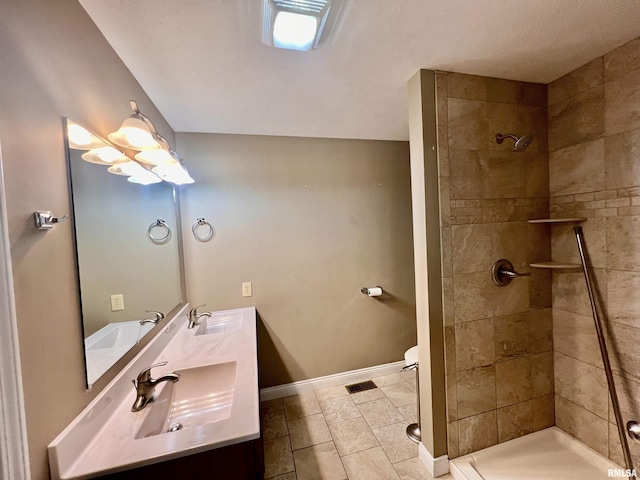 bathroom featuring vanity, a tile shower, tile patterned floors, and toilet