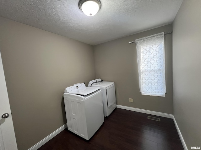 laundry area featuring dark wood-type flooring, washing machine and clothes dryer, and a textured ceiling