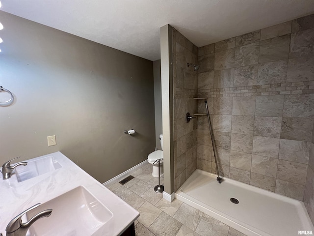 bathroom with vanity, toilet, and tiled shower