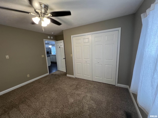 unfurnished bedroom featuring ceiling fan, dark carpet, and a closet