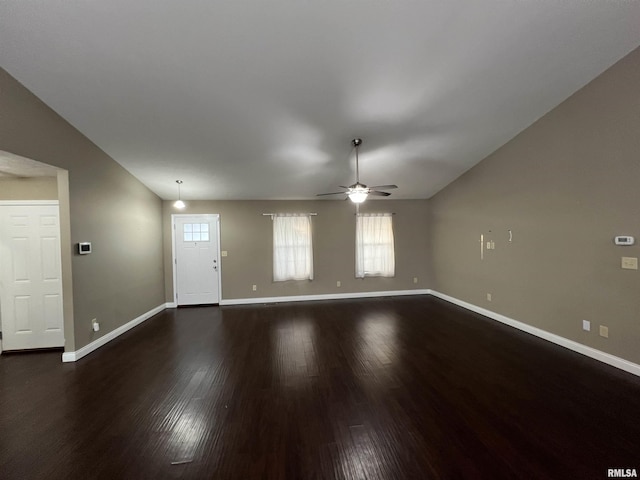 unfurnished living room with dark hardwood / wood-style flooring, vaulted ceiling, and ceiling fan