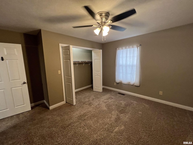 unfurnished bedroom with ceiling fan, a closet, and dark colored carpet