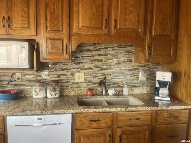 kitchen with backsplash, white appliances, sink, and stone counters