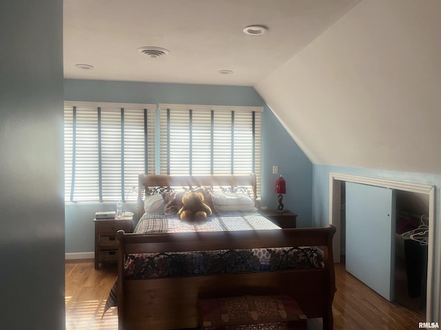 bedroom with lofted ceiling, wood-type flooring, and a closet