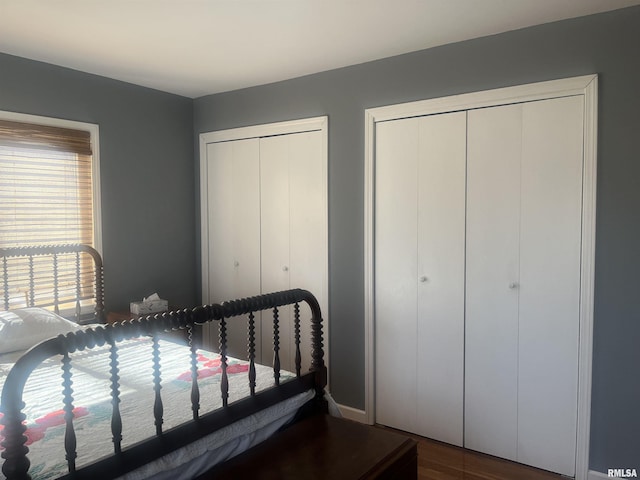 bedroom with hardwood / wood-style flooring and two closets