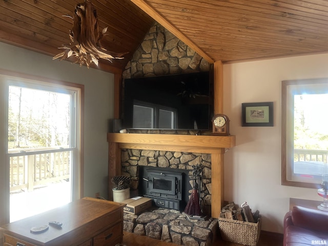 living room featuring vaulted ceiling, a healthy amount of sunlight, a wood stove, and wooden ceiling