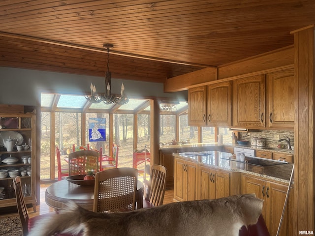 kitchen featuring lofted ceiling, wood ceiling, an inviting chandelier, light stone counters, and decorative light fixtures