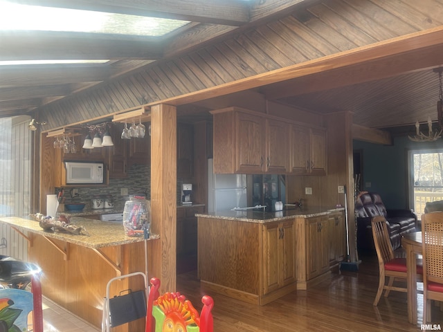 kitchen with wood-type flooring, white appliances, and kitchen peninsula