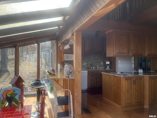 kitchen featuring sink, white appliances, dark wood-type flooring, stone counters, and backsplash