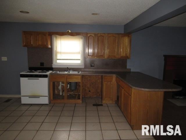 kitchen featuring light tile patterned flooring, sink, white range with gas cooktop, kitchen peninsula, and a textured ceiling