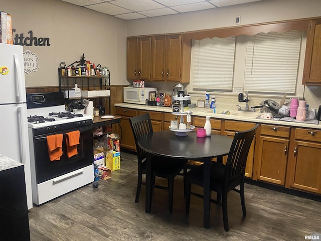 kitchen with a drop ceiling, sink, white appliances, and dark hardwood / wood-style floors