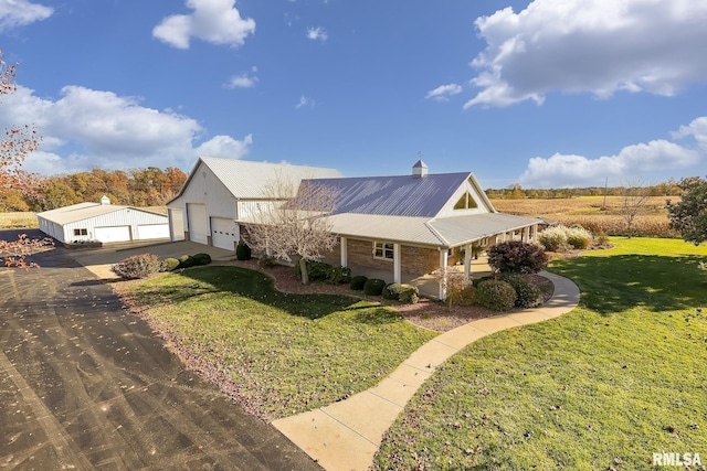 view of front facade with a front lawn, aphalt driveway, a porch, an outbuilding, and a garage