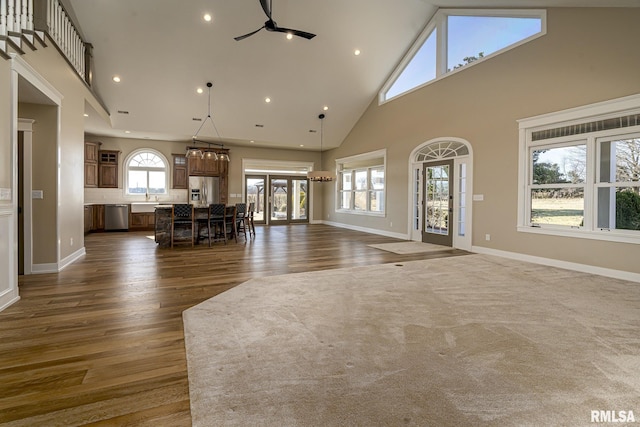 unfurnished living room featuring ceiling fan, a healthy amount of sunlight, sink, and dark hardwood / wood-style flooring