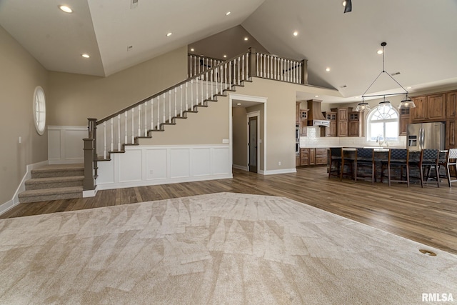 unfurnished living room with dark hardwood / wood-style floors, sink, and high vaulted ceiling