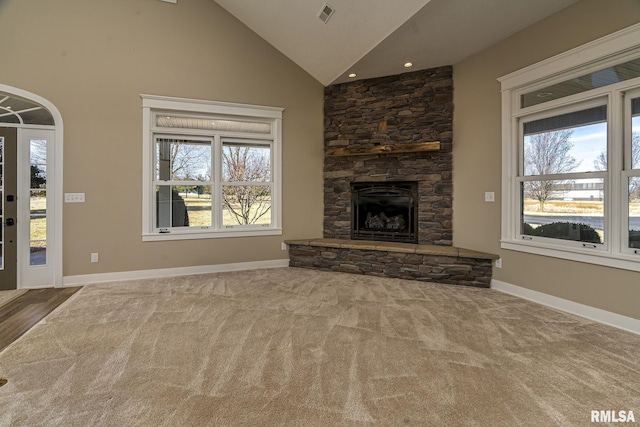 unfurnished living room featuring a stone fireplace, carpet, and high vaulted ceiling