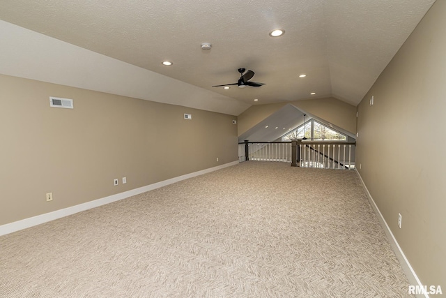 additional living space with ceiling fan, light colored carpet, vaulted ceiling, and a textured ceiling