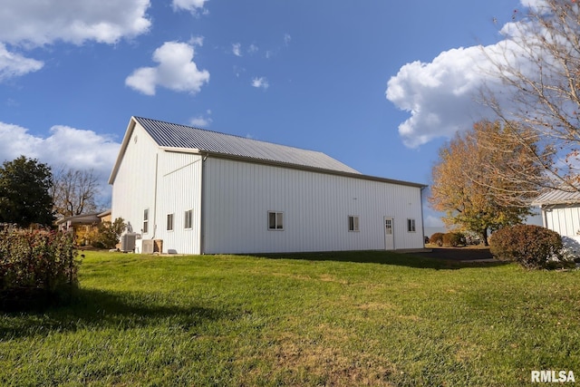 view of side of property featuring a pole building, central AC, an outdoor structure, a lawn, and metal roof