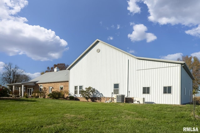 rear view of house featuring cooling unit, board and batten siding, and a lawn