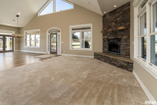 unfurnished living room with a fireplace, high vaulted ceiling, and light carpet