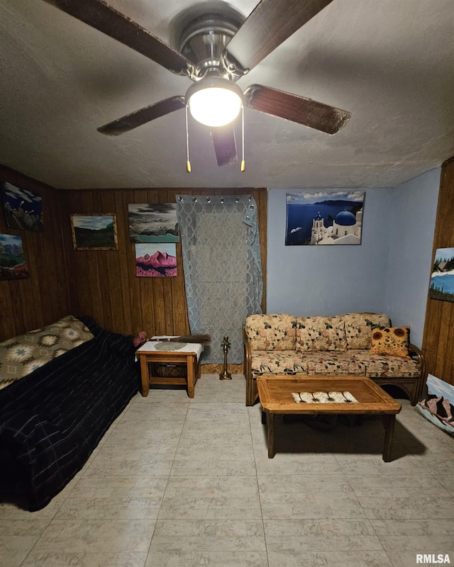 bedroom with ceiling fan, a textured ceiling, and wooden walls