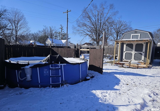 yard covered in snow featuring a shed and a fenced in pool