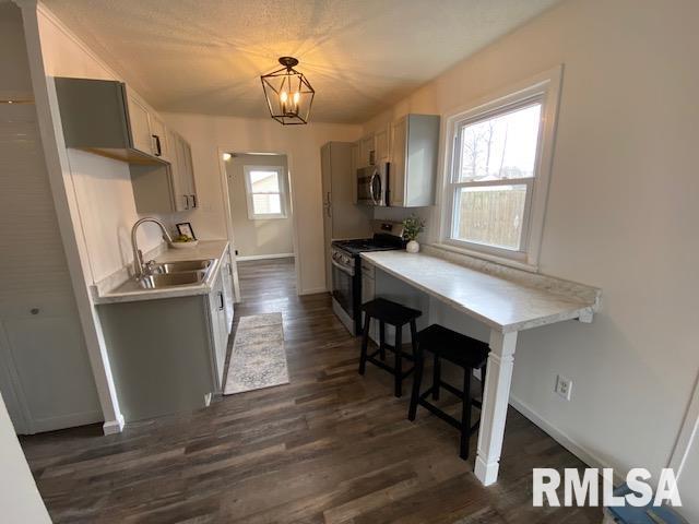 kitchen with appliances with stainless steel finishes, sink, dark hardwood / wood-style floors, and decorative light fixtures