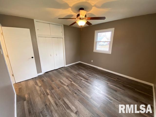 unfurnished bedroom with dark wood-type flooring, ceiling fan, and a closet