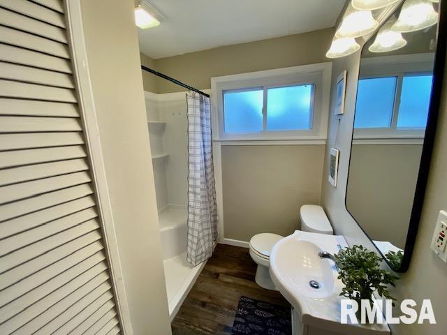 full bathroom featuring wood-type flooring, a wealth of natural light, shower / tub combo, and toilet