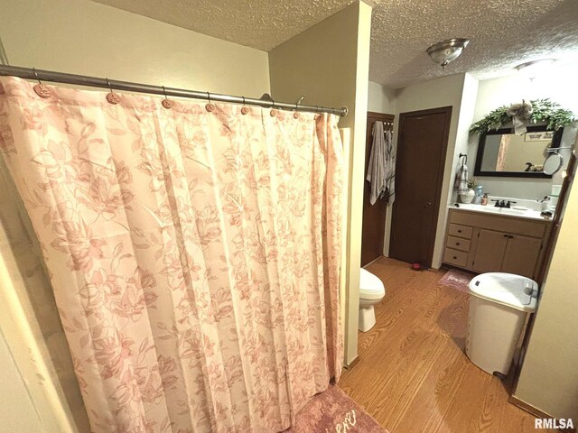 bathroom featuring vanity, hardwood / wood-style floors, toilet, and a textured ceiling