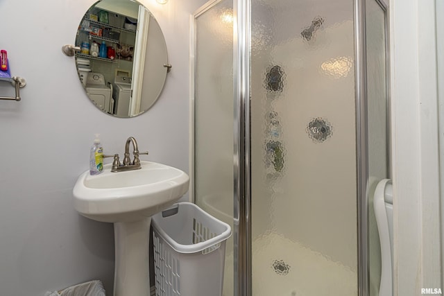 bathroom featuring walk in shower, washer / clothes dryer, and sink