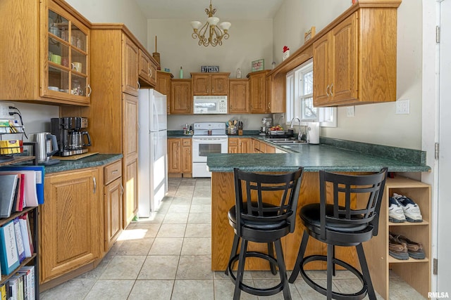 kitchen with light tile patterned flooring, sink, a breakfast bar area, kitchen peninsula, and white appliances