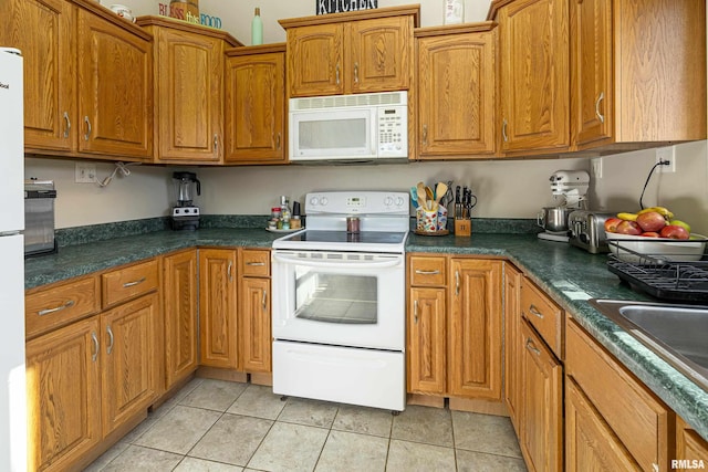 kitchen with sink, white appliances, and light tile patterned flooring