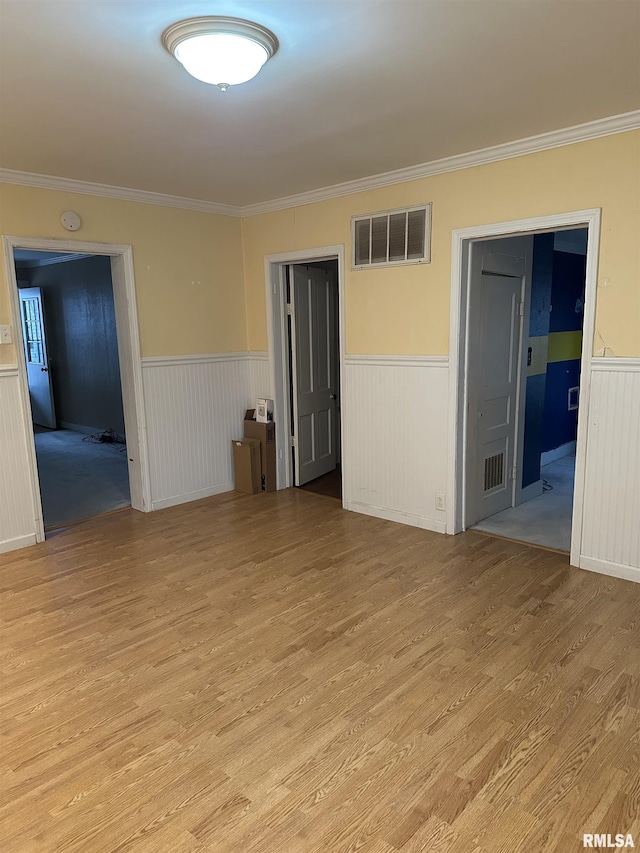 empty room featuring ornamental molding and light wood-type flooring