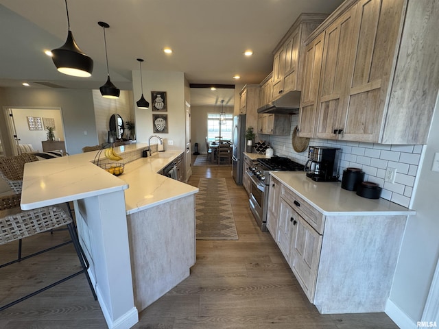 kitchen with hardwood / wood-style flooring, appliances with stainless steel finishes, a kitchen breakfast bar, decorative backsplash, and decorative light fixtures