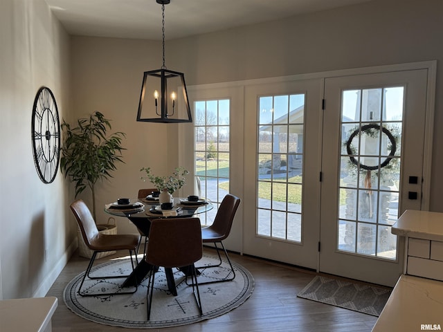 dining space with a healthy amount of sunlight, dark hardwood / wood-style flooring, and a notable chandelier