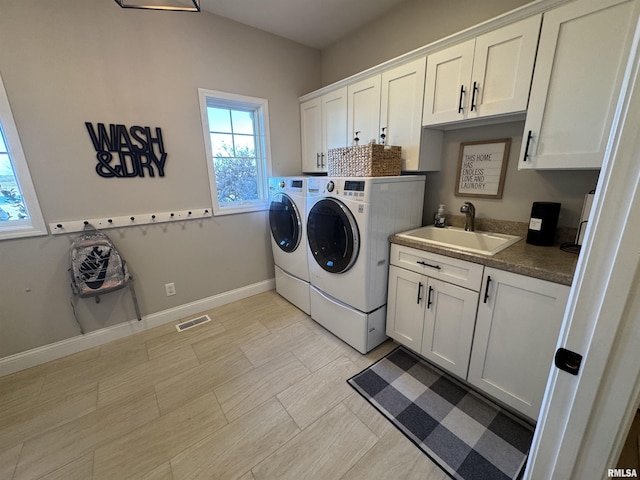 clothes washing area with cabinets, sink, and washer and clothes dryer